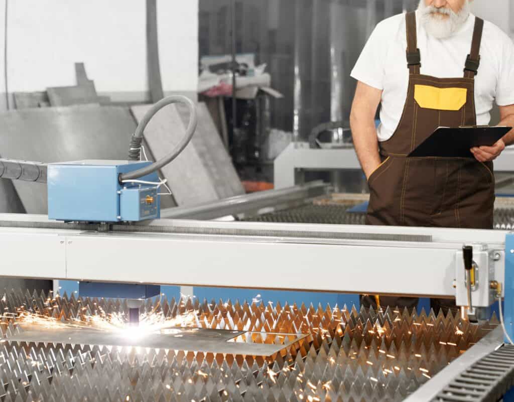 Industrial steel cutting machine in action with a technician overseeing the process.